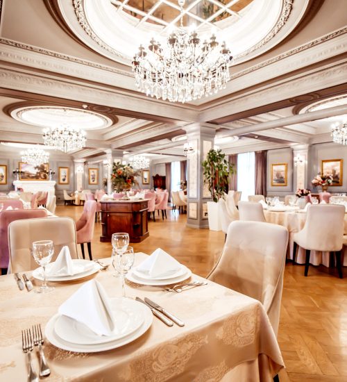 restaurant hall with round and square tables some chairs and plants
